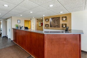 A reception desk with a wooden finish, a clock, and a wall-mounted information board. - Comfort Inn & Suites Jackson - West Bend (Jackson)