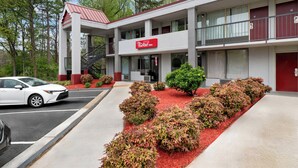 Un Red Roof Inn avec un toit rouge, une entrée abritée et un jardin aménagé avec du paillis rouge et des arbustes.