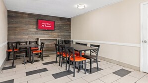 Une salle de conférence avec un mur en bois, un panneau rouge indiquant que le Wi-Fi est gratuit, et un sol carrelé.