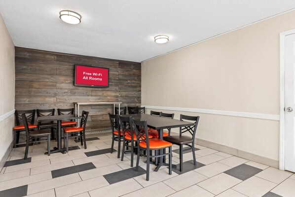 Une salle de conférence avec un mur en bois, un panneau rouge indiquant que le Wi-Fi est gratuit, et un sol carrelé.