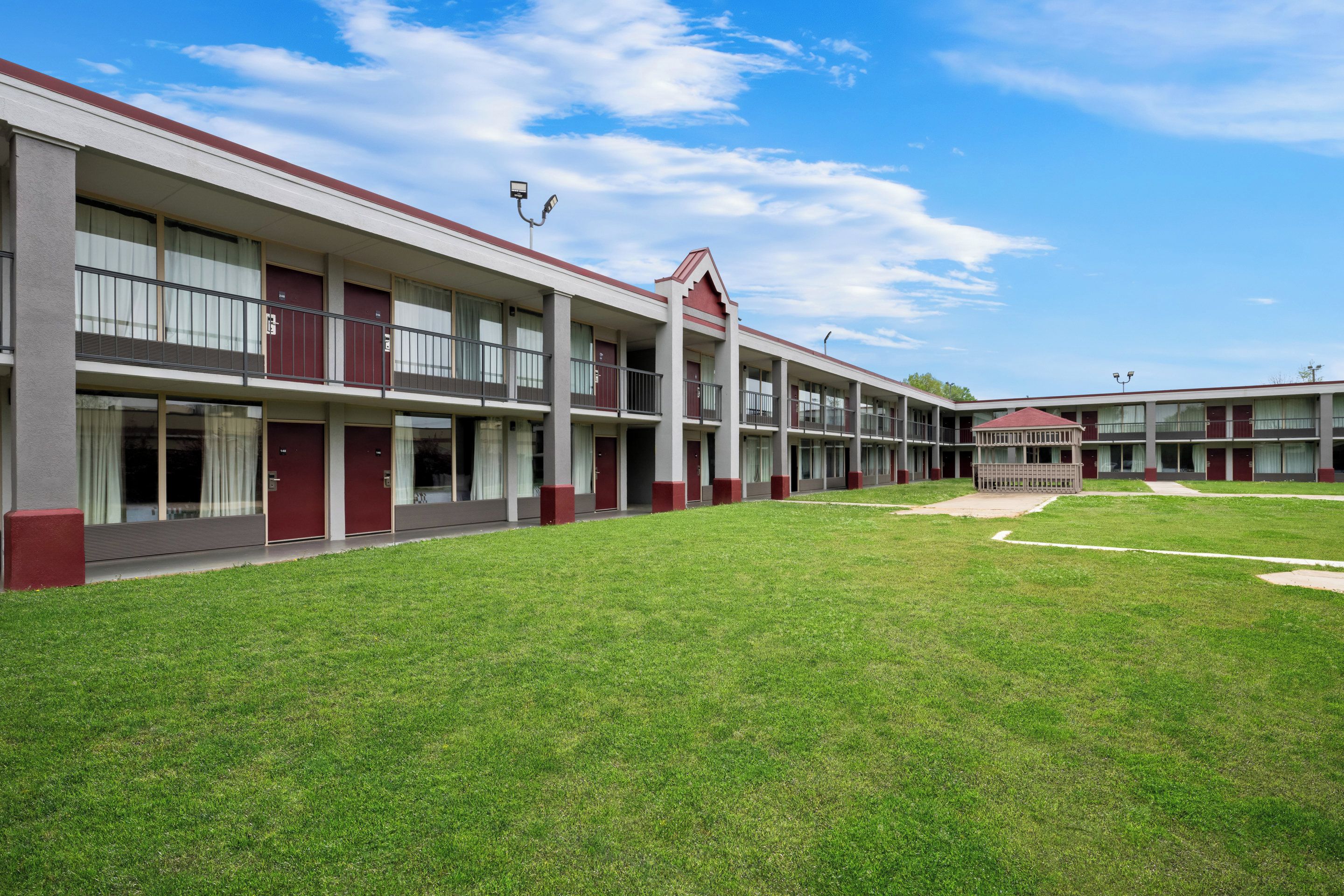 Un hotel de varios pisos con un patio central, destacando una fachada simétrica con detalles rojos, amplias ventanas y techo plano.
