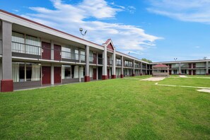 A multi-story hotel with a central courtyard, featuring a symmetrical facade with red accents, large windows, and a flat roof.