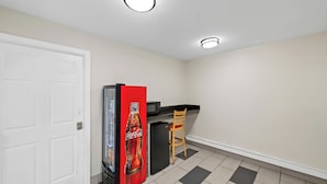 Una cocina compacta con refrigerador, lavamanos y una silla.