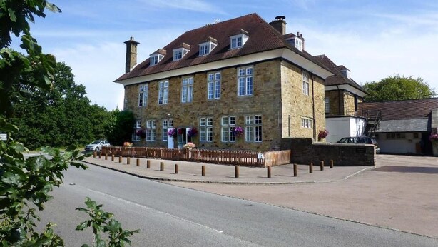 A stone building with a pitched roof, multiple windows, and a paved area in front. - The Speech House Hotel (Coleford)