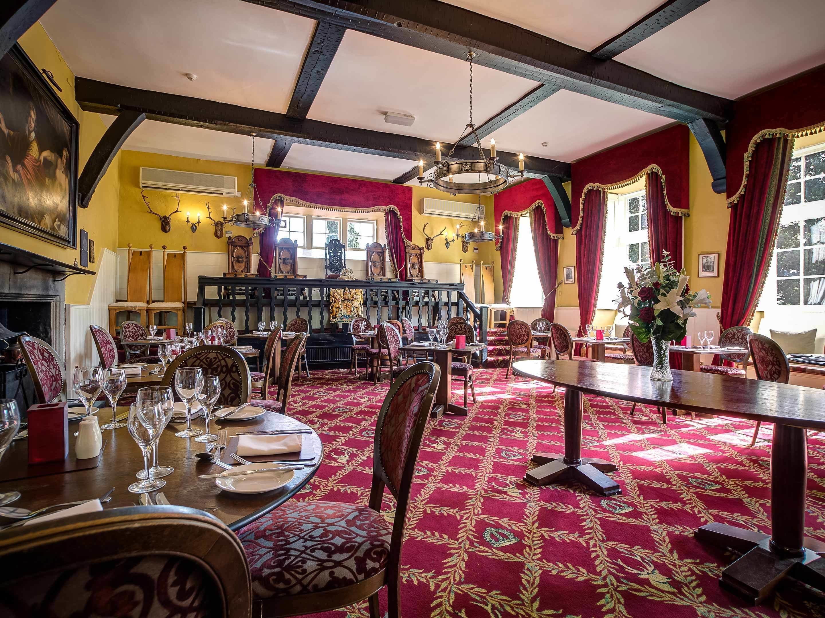 A dining area with round tables, red carpets, and wooden chairs.