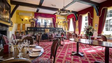 A dining area with round tables, red carpets, and wooden chairs.