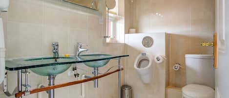 A bathroom with a glass sink, a toilet, and a bidet.