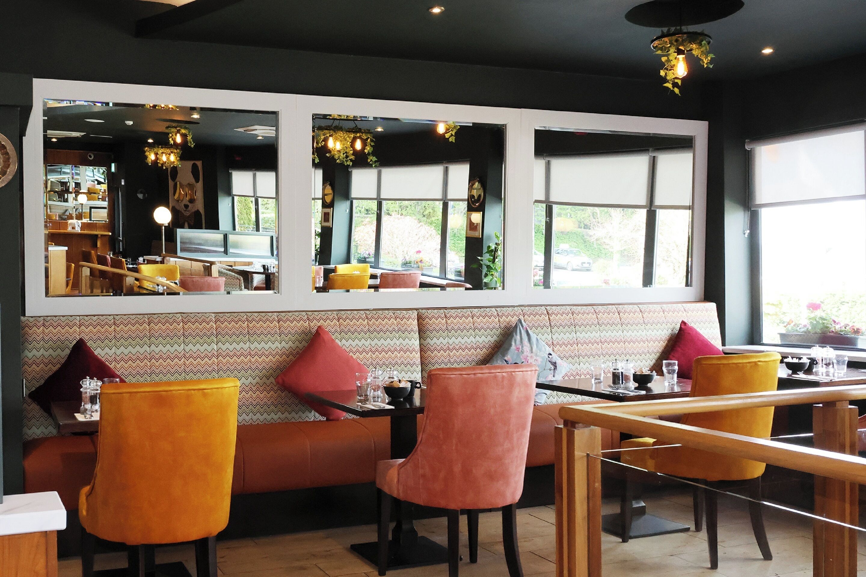 Un restaurante con una decoración moderna, que cuenta con una barra larga, varias zonas de estar con sillas acolchadas y amplios ventanales que permiten la entrada de luz natural.