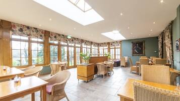 A spacious indoor area with multiple seating arrangements, large windows, and a skylight.