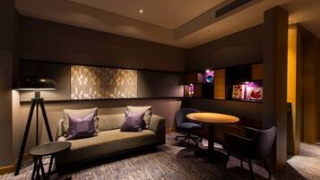 A modern lounge area with a sofa, chairs, a small table, and a lamp.