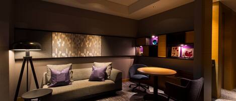 A modern lounge area with a sofa, chairs, a small table, and a lamp.