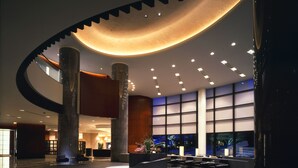 A spacious lobby with a curved ceiling, large columns, and a central seating area with a flower arrangement.