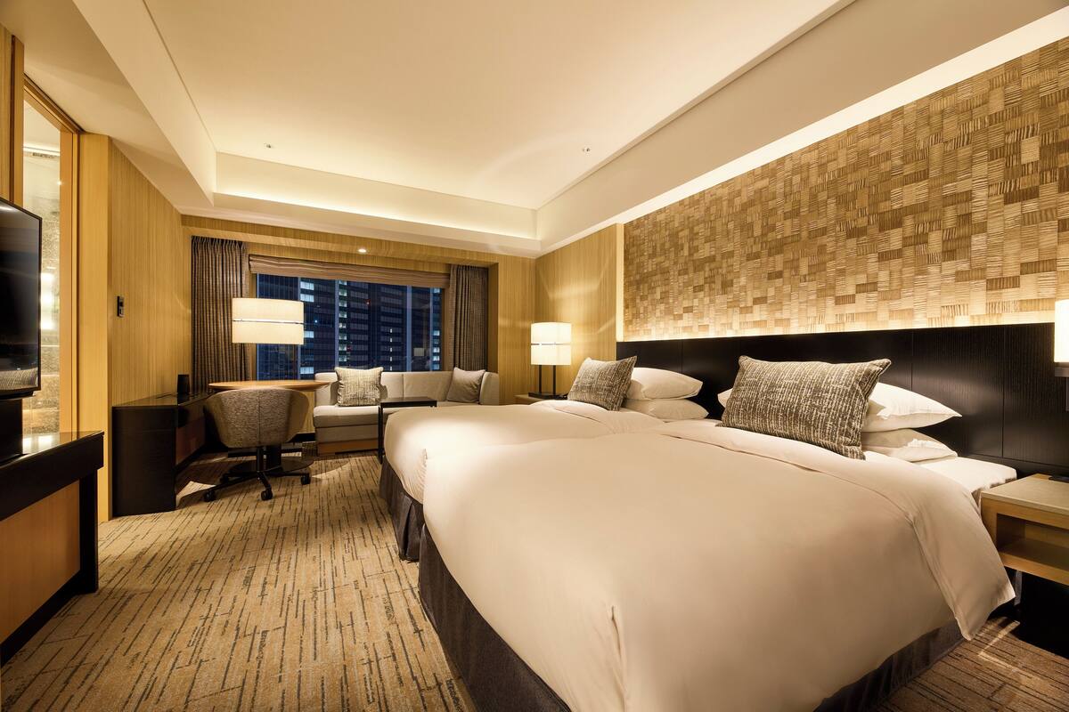 A hotel room with a large bed, a desk, a chair, and a TV.