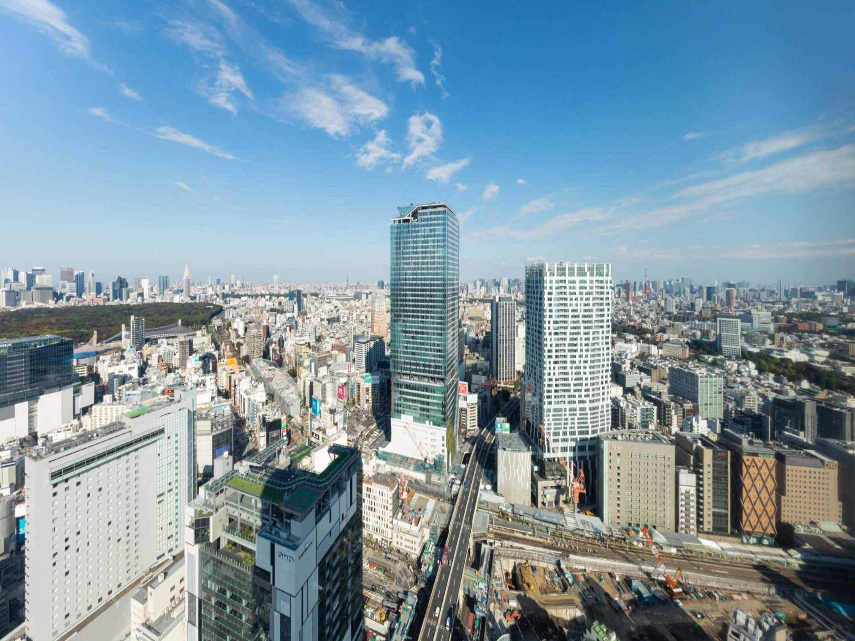 A cityscape with modern high-rise buildings, a busy street, and a clear blue sky.