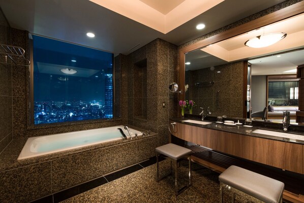 A modern bathroom with a large bathtub, dual sinks, and a large mirror.