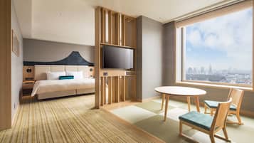 Camera d'hotel con un letto, una TV, un tavolo da pranzo con sedie e vista sulla città.