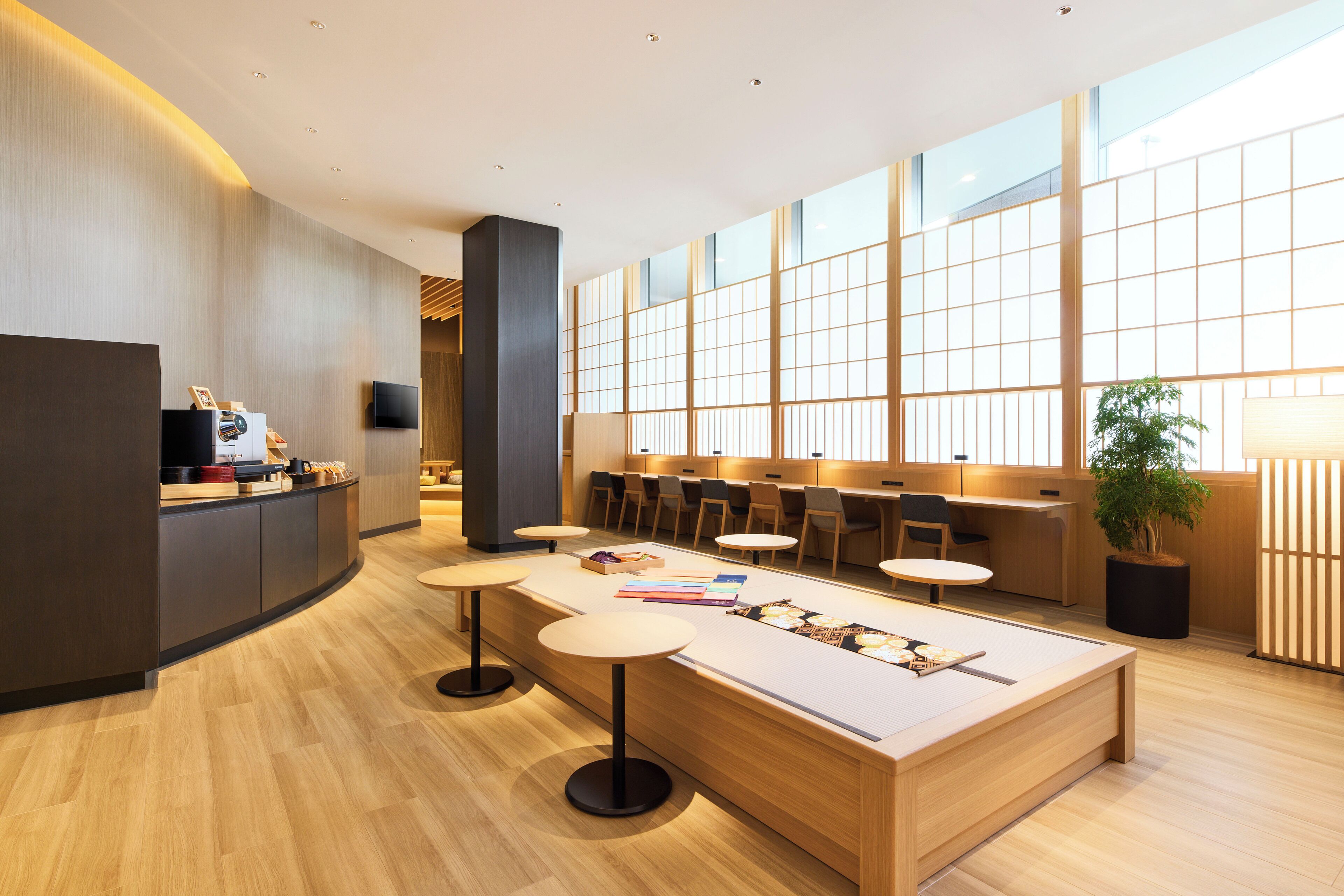 Un vestíbul d'hotel modern amb taulell de recepció, zona de seients i grans finestres.