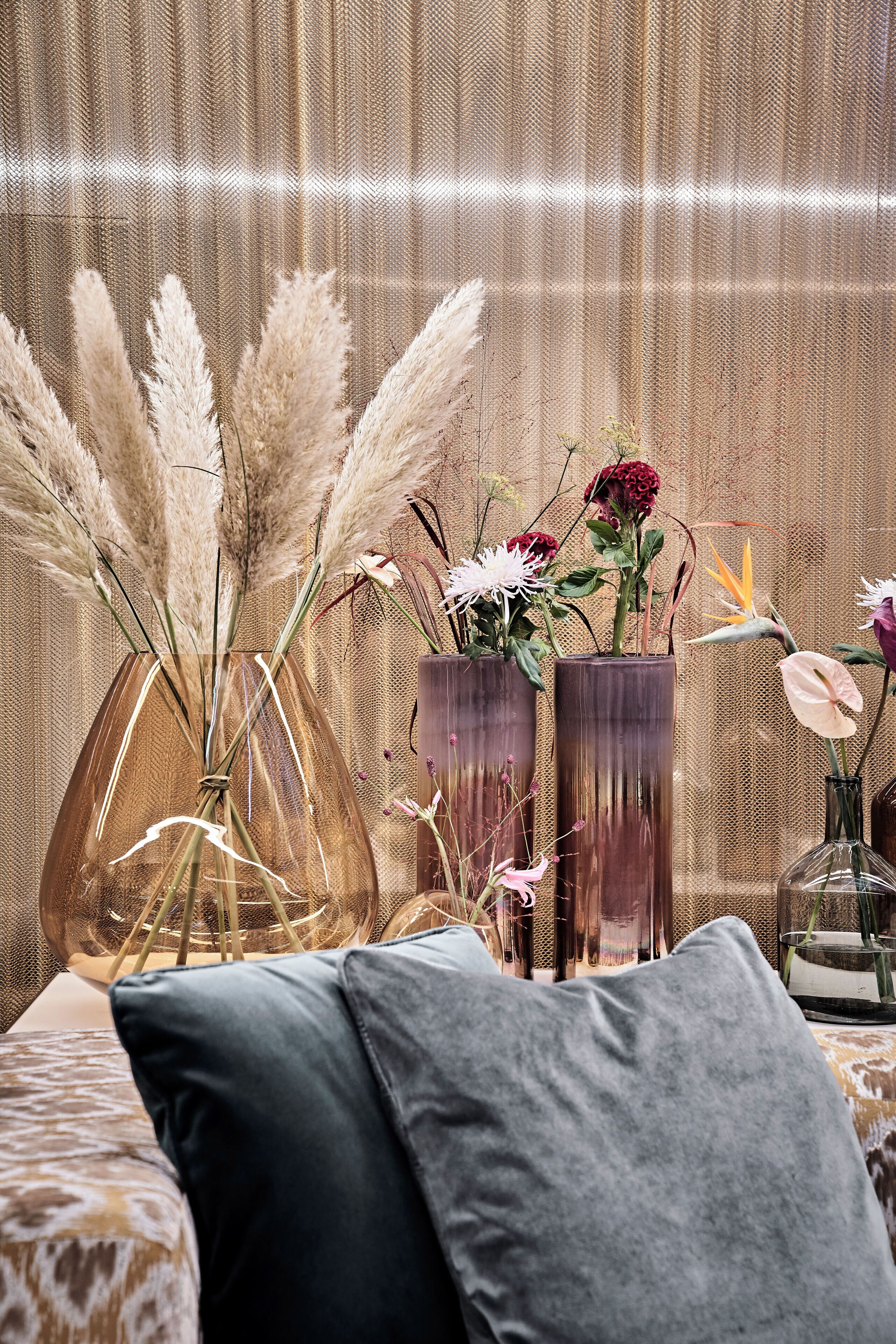 A room with a bed, a bedside table with a vase of flowers, and a textured wall.