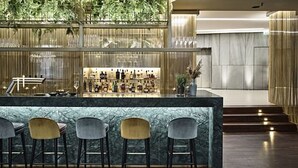 Una zona de bar con mostrador de mármol y cuatro taburetes.