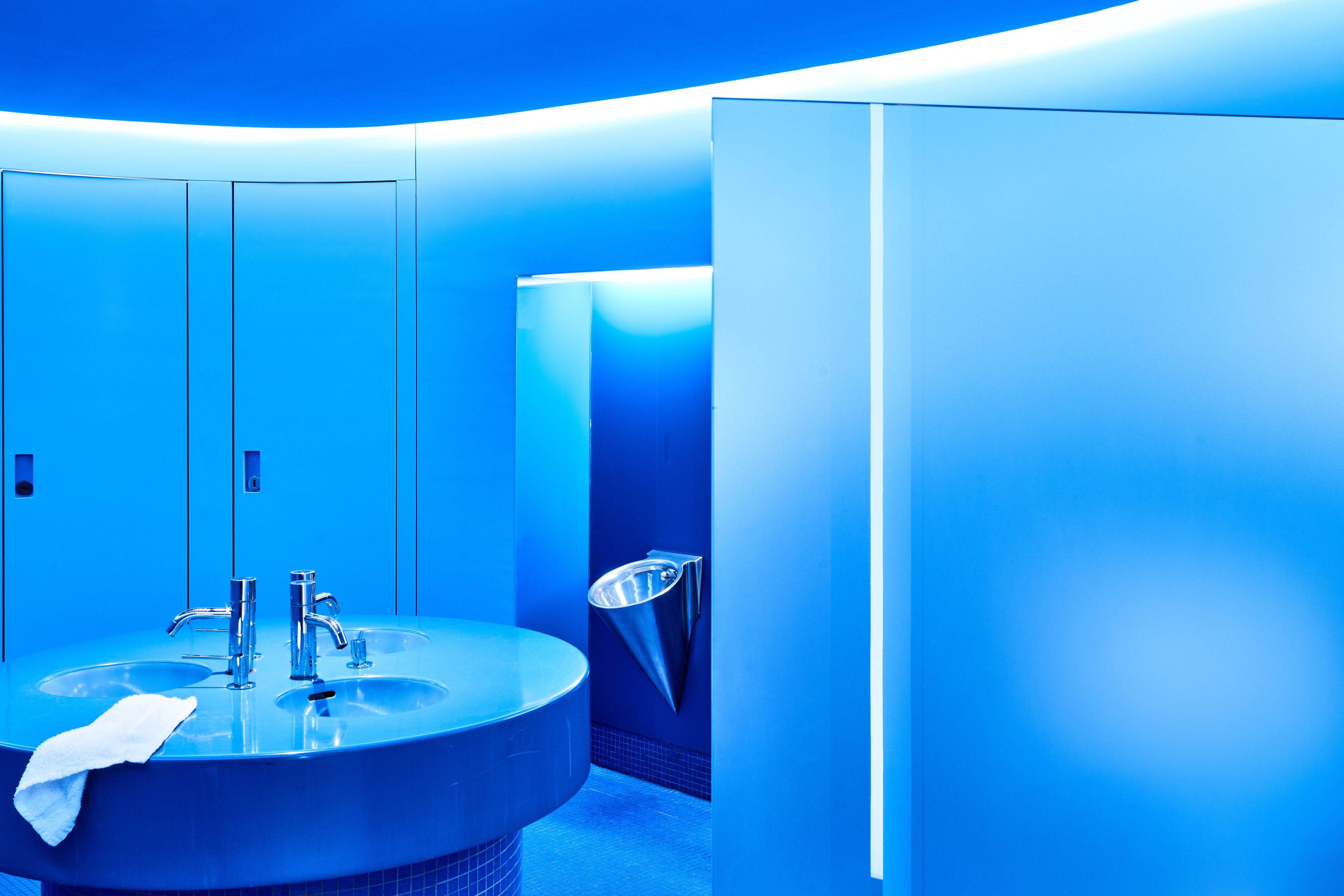 A modern bathroom with a large round sink, two faucets, and a towel on the sink.