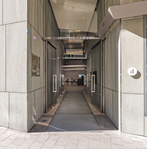 A modern building entrance with a glass door, a metal ramp, and a tiled floor. - SIDE, a Member of Design Hotels (Hamburg)