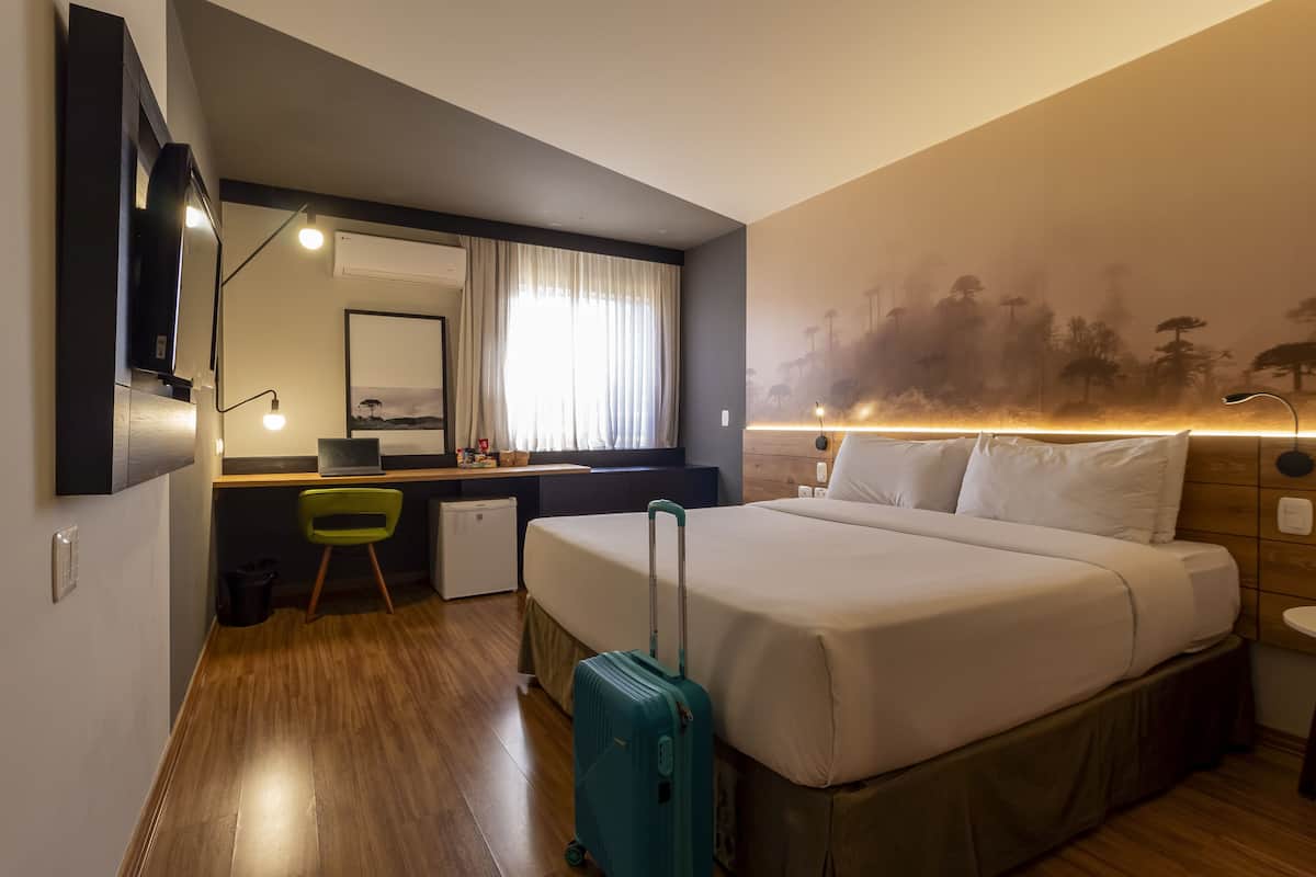 Habitació d'hotel amb llit, escriptori, cadira i petita cuineta.