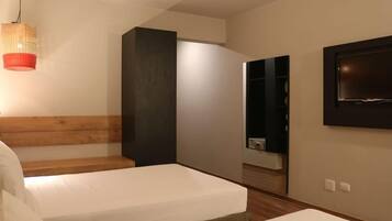 A modern bedroom with two beds, a wooden headboard, a large mirror, and a TV mounted on the wall.