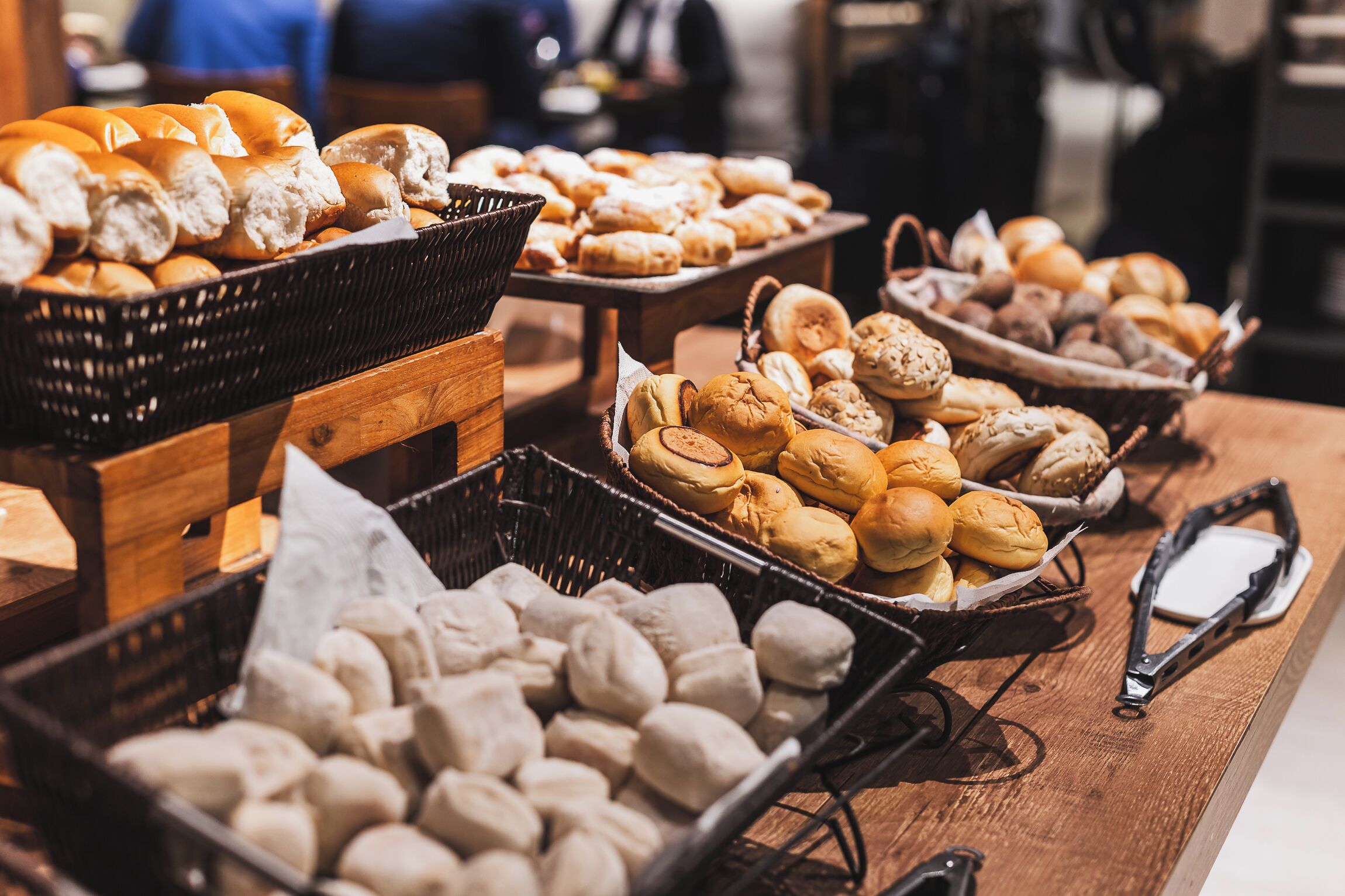 A variety of baked goods displayed on wooden tables in a bakery setting.