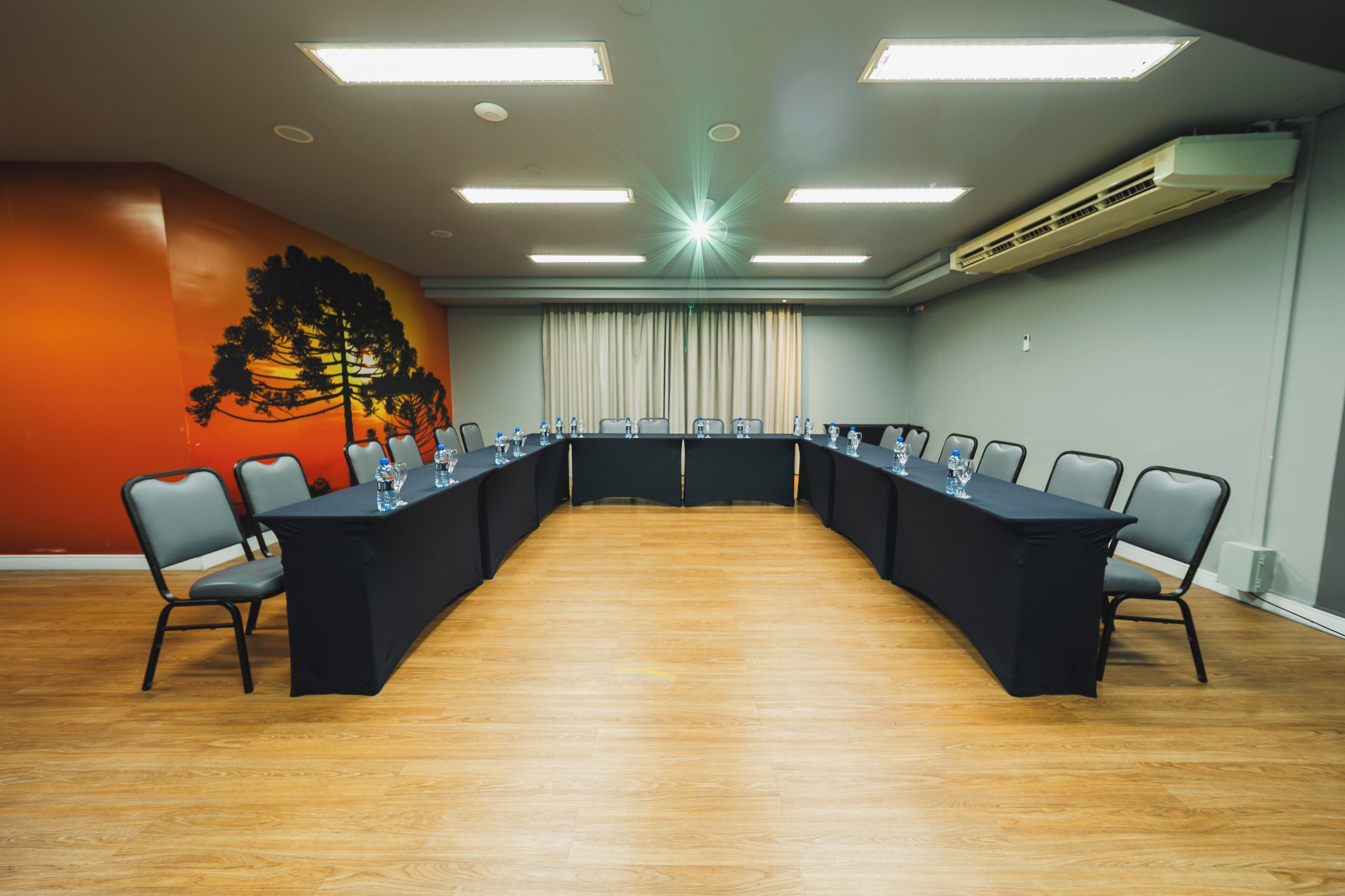 A conference room with a long table, chairs, and a large window with curtains.