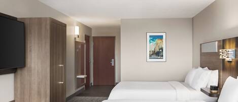 Una habitación de hotel con cama, televisión, armario y baño.