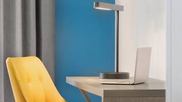 Een moderne bureaustoel, een bureau met een laptop en een vloerlamp.