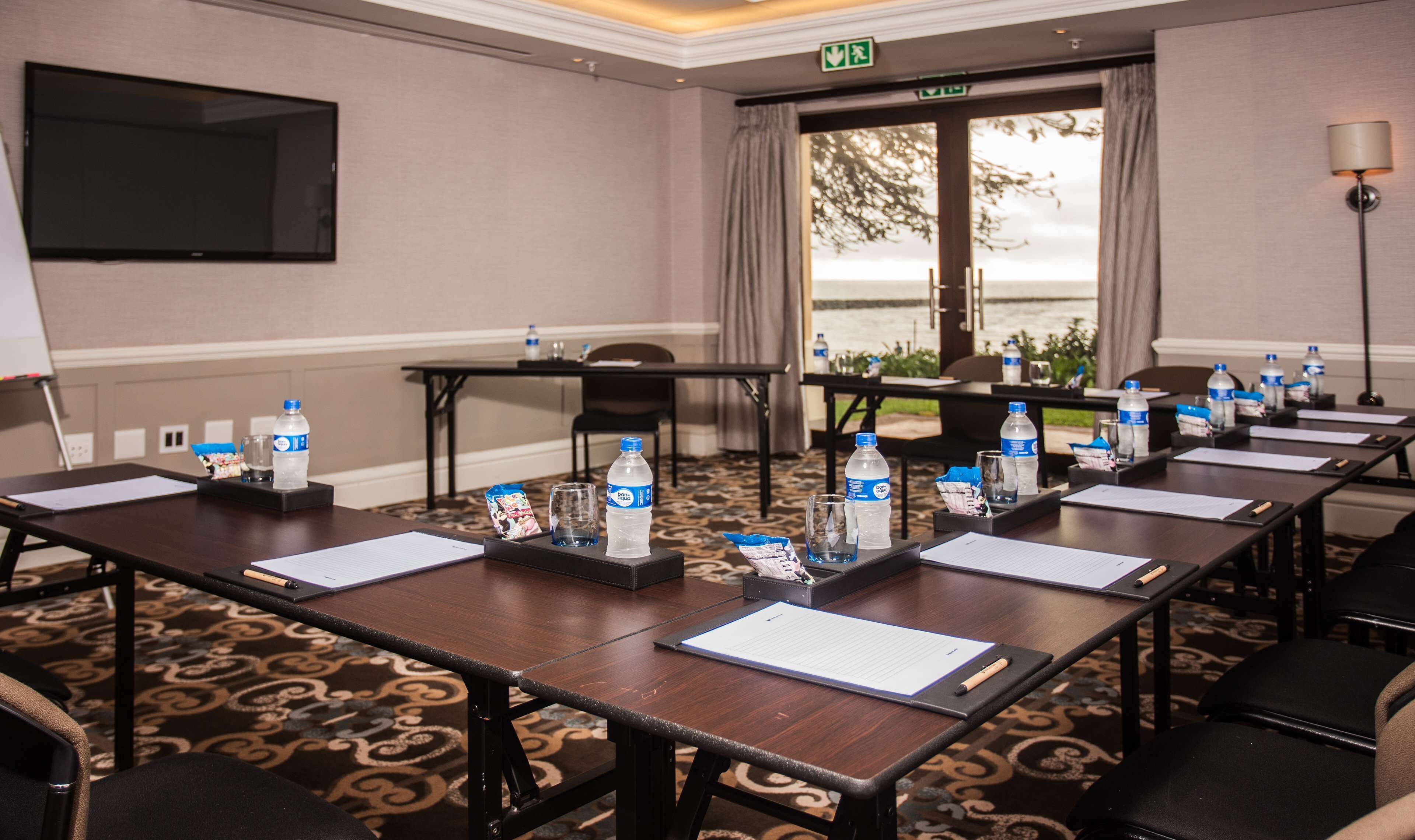 Un salón de conferencias con una mesa grande, botellas de agua y documentos.