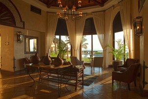 A spacious lobby with a large table, comfortable seating, and large windows offering a view of the outdoors.