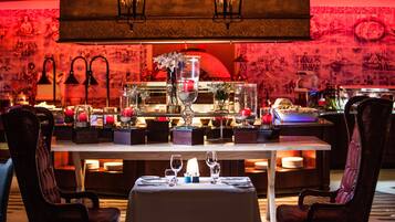 A restaurant with a table set for two, featuring a candle centerpiece, wine glasses, and a vase with flowers.