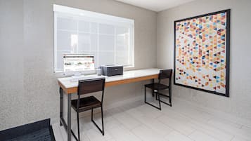 A modern office space with a desk, two chairs, a computer, and a large window.