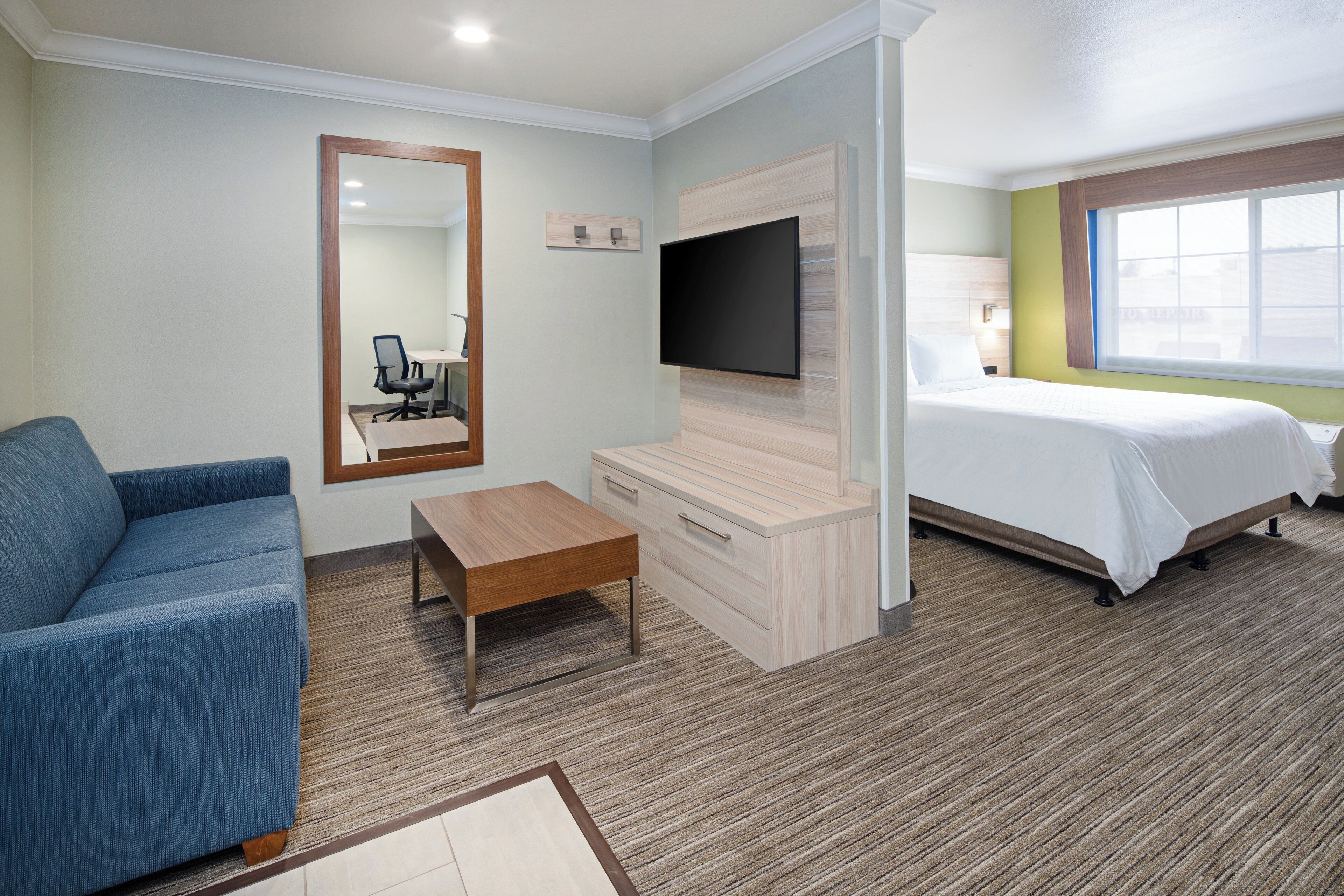 Una habitación de hotel con cama, sofá, televisión, escritorio y ventana.
