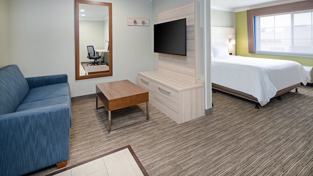 A hotel room with a bed, a sofa, a TV mounted on the wall, a desk, and a window. - Holiday Inn Express & Suites Watsonville by IHG (Watsonville)