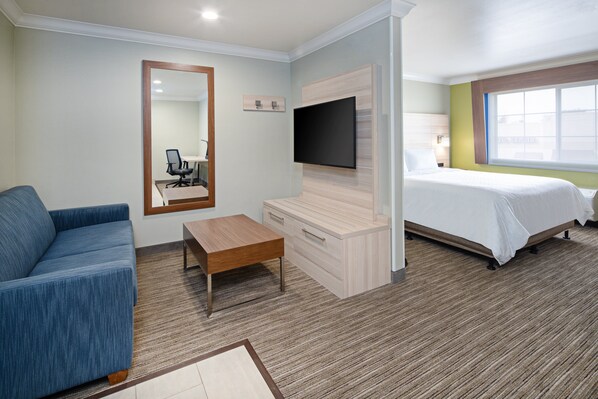 Hotelkamer met een bed, een bank, een televisie aan de muur, een bureau en een raam.