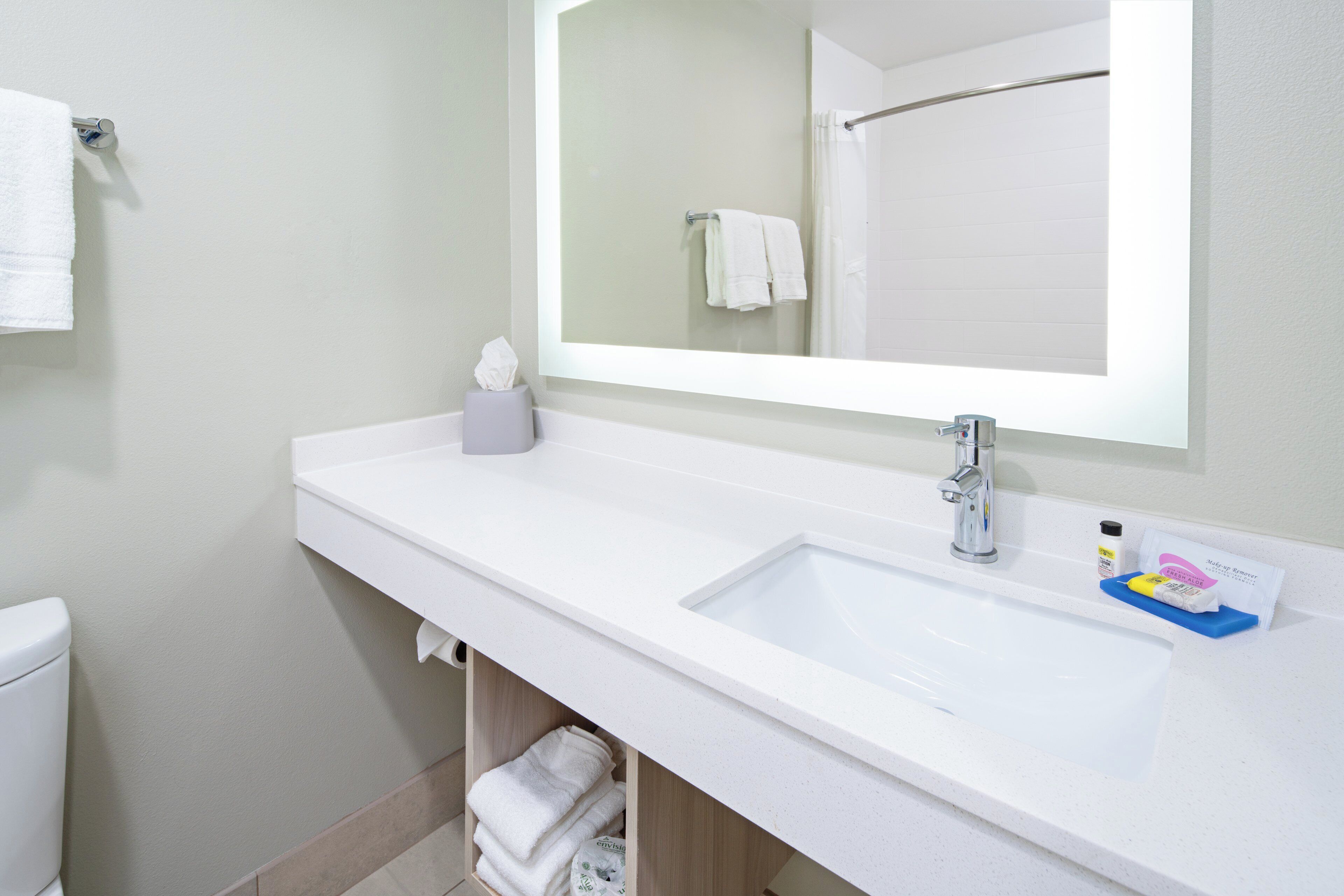 Een badkamer met een witte wastafel, een spiegel, een handdoekhouder en een toilet.