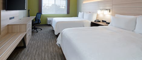 A hotel room with two beds, a desk, a chair, a television, and a window.