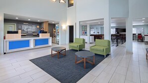A hotel lobby with a reception desk, seating area, and a dining area.