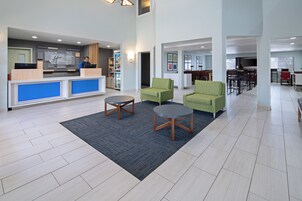 Un vestíbulo de hotel con recepción, zona de estar y comedor.