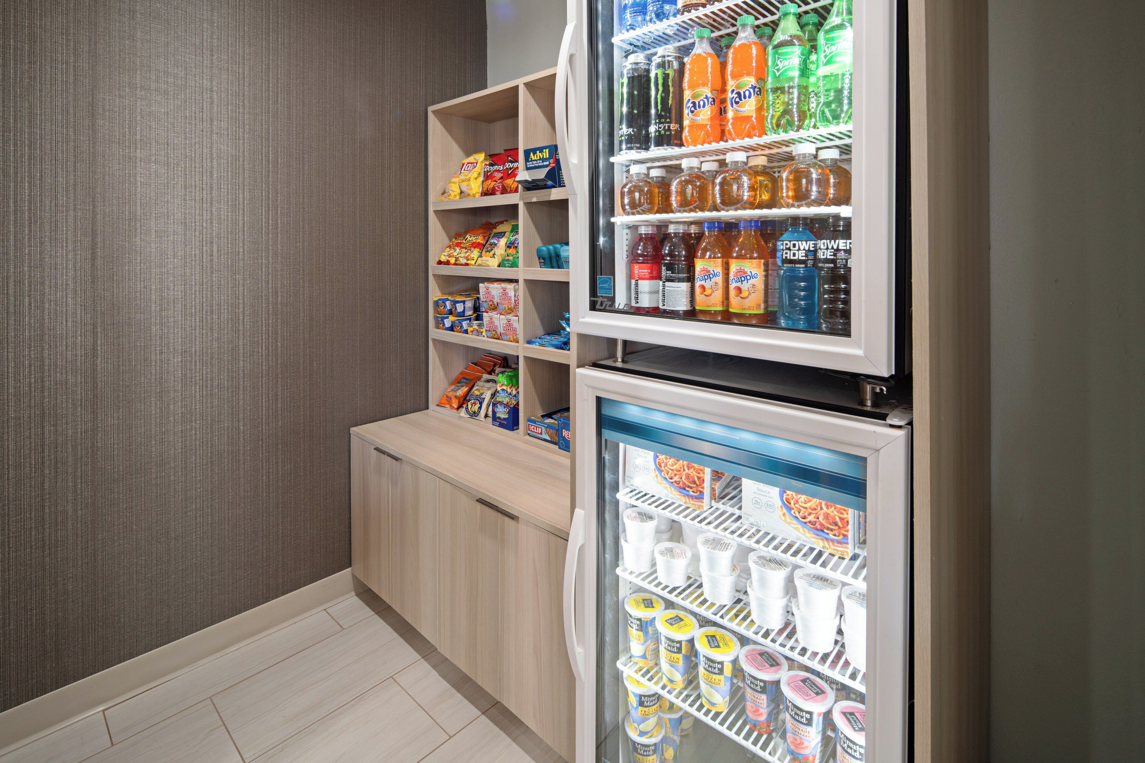 A mini-fridge stocked with beverages and a freezer with frozen desserts.