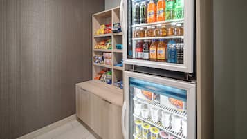 A mini-fridge stocked with beverages and a freezer with frozen desserts.