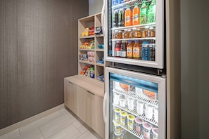 A mini-fridge stocked with beverages and a freezer with frozen desserts.