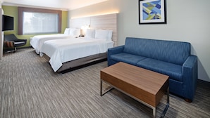 A hotel room with two beds, a blue sofa, a wooden coffee table, a TV, and a framed picture on the wall. - Holiday Inn Express & Suites Watsonville by IHG (Watsonville)