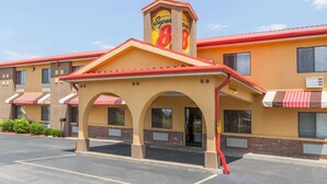 Un hotel Super 8 con fachada roja y amarilla, varios arcos y un estacionamiento.
