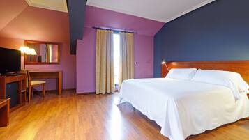 A hotel room with a wooden bed, a desk with a lamp, and a television.
