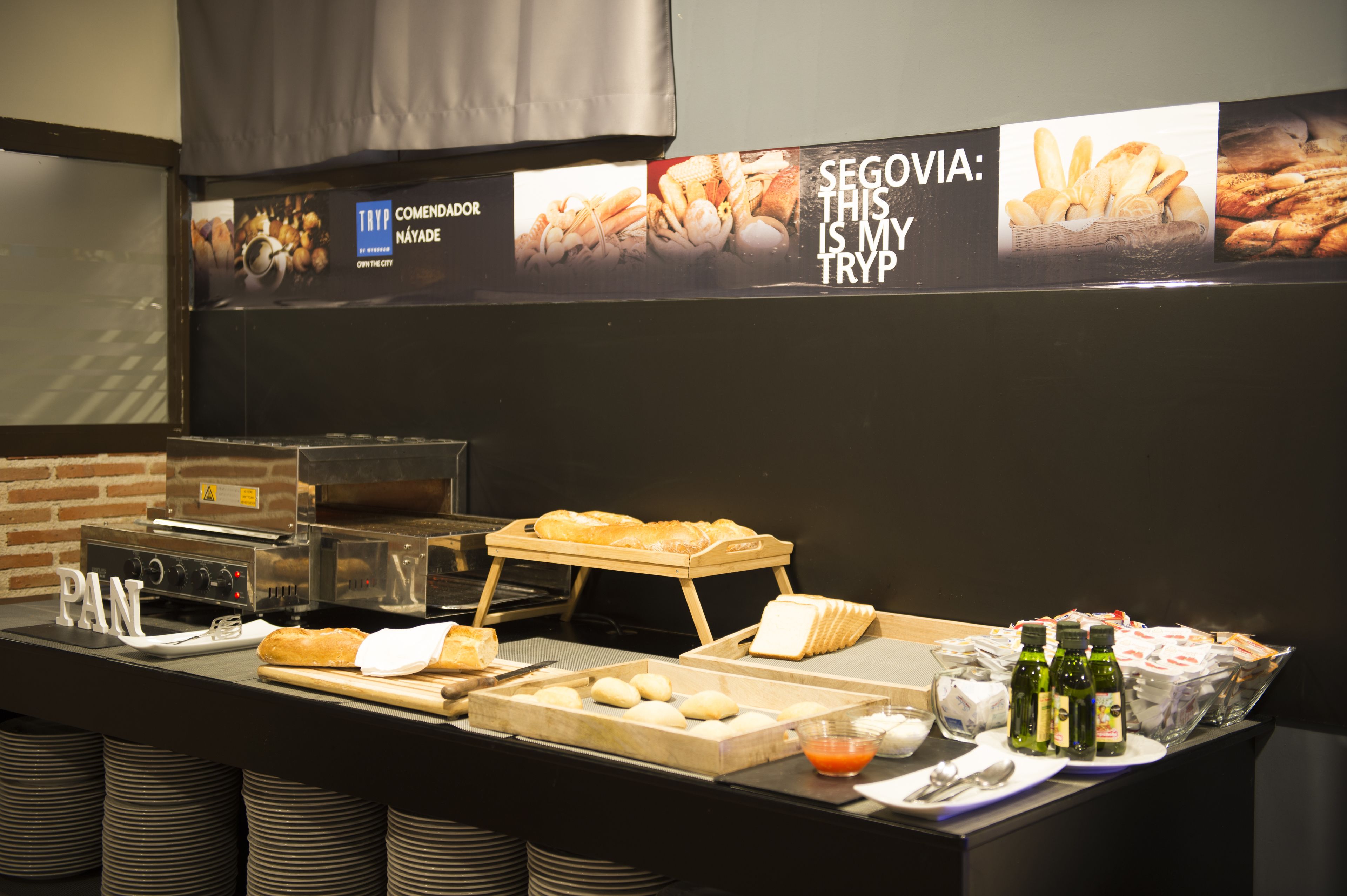 A breakfast buffet with various breads, pastries, and beverages.