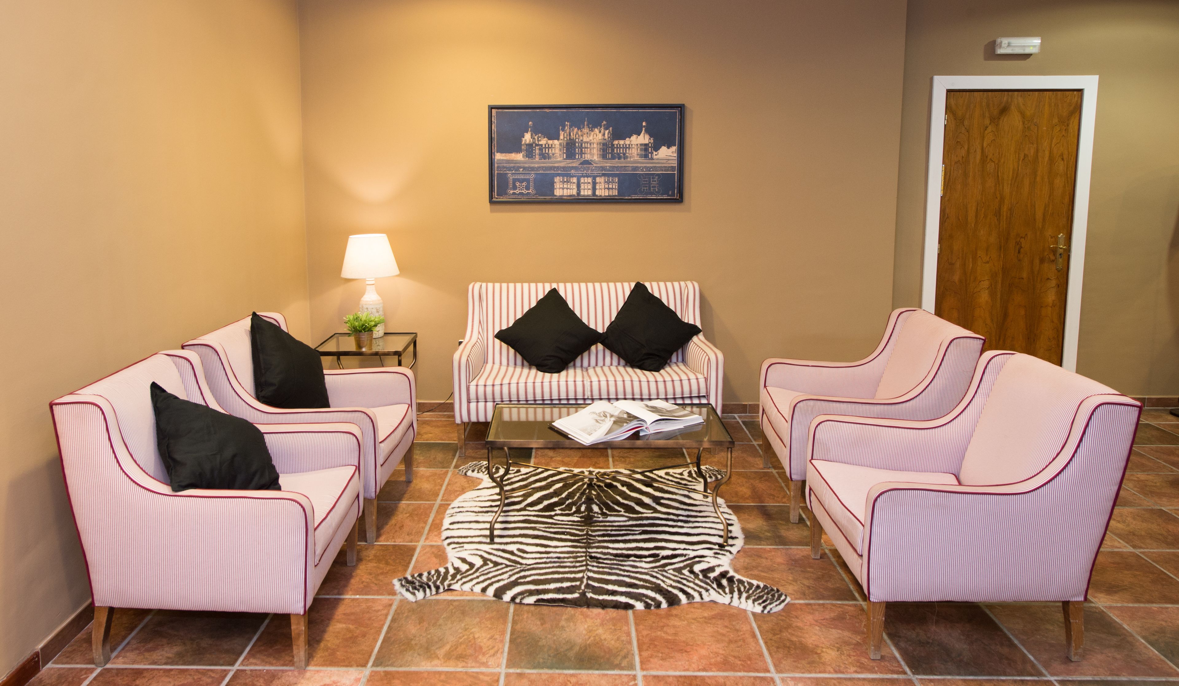 A room with striped furniture, a zebra rug, a lamp, and a framed picture on the wall.